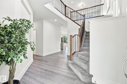 Spacious entry with wood-finish flooring, a carpeted staircase, and a wood and metal railing - 