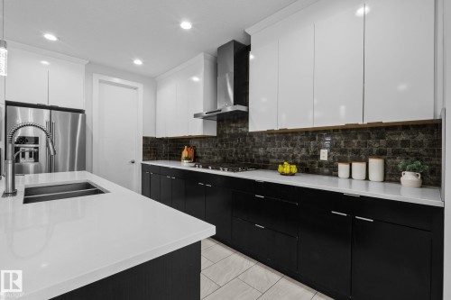 Modern kitchen featuring stainless steel appliances, dual-tone cabinetry, stone countertops, and a tiled backsplash - 2019 Ware Rd Nw, Edmonton, AB 