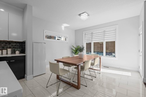 White tile flooring, contemporary ceiling light fixture, large windows with blinds, sleek cabinetry, and a dark tile backsplash - 2019 Ware Rd Nw, Edmonton, AB 