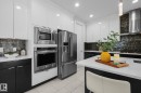 Contemporary kitchen featuring stainless steel appliances, a built-in microwave and oven, a side-by-side refrigerator, white upper cabinetry, and dark lower cabinetry - 2019 Ware Rd Nw, Edmonton, AB 