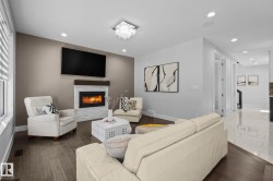 Living area featuring a stone-faced fireplace with a wood mantel, wood-finish flooring, recessed lighting, and a contemporary ceiling fixture - 