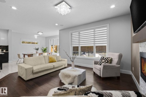 Spacious living area featuring dark wood-finish flooring, recessed lighting, and a modern ceiling fixture - 2019 Ware Rd Nw, Edmonton, AB 