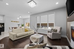 Spacious living area featuring dark wood-finish flooring, recessed lighting, and a modern ceiling fixture - 