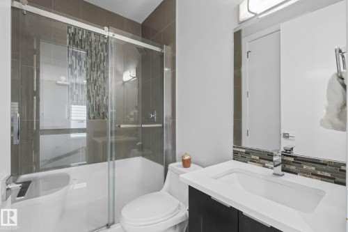 Modern bathroom featuring a vanity with an integrated sink, polished chrome faucet, and a large mirror - 2019 Ware Rd Nw, Edmonton, AB 