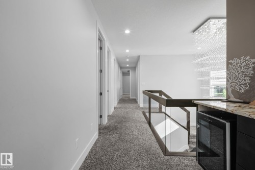 Hallway with recessed lighting, carpeted flooring, and a glass-paneled railing - 2019 Ware Rd Nw, Edmonton, AB 