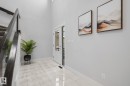 Two-story entry with a wood handrail, glass balusters, and light-toned tile flooring - 2019 Ware Rd Nw, Edmonton, AB 