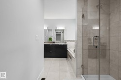 Spacious bathroom featuring a glass-enclosed shower, built-in soaking tub, and a vanity with a stone countertop - 