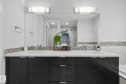 Dual vanity with integrated sinks, contemporary cabinetry, a mosaic tile backsplash, and overhead lighting fixtures - 