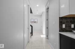 Hallway featuring light-toned tile flooring, recessed lighting, and white walls - 