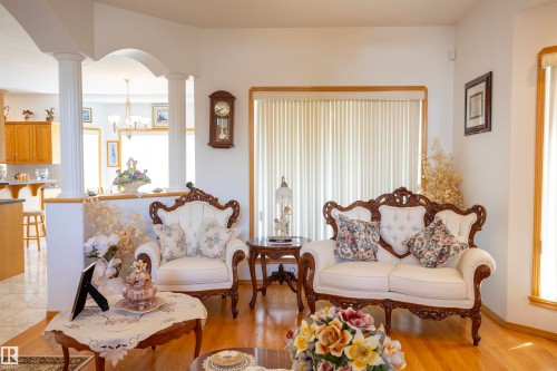 Hardwood flooring throughout this living area, featuring an arched entryway with decorative columns - 6407 163 Avenue Nw, Edmonton, AB 