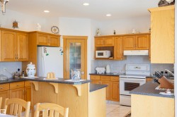 Kitchen featuring light wood cabinetry, stone-finish countertops, tile backsplash, and recessed lighting - 