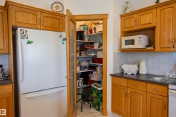 Kitchen featuring light wood-finish cabinetry, a freestanding refrigerator, and a pantry with a wood-frame glass door - 
