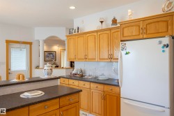 Kitchen with wood-finish cabinetry, dark countertops, and a white refrigerator - 