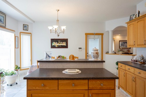 Kitchen island with dark countertop and light wood cabinetry - 6407 163 Avenue Nw, Edmonton, AB 