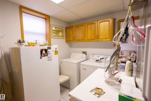 Utility space featuring a window, overhead cabinetry, and white tile flooring - 6407 163 Avenue Nw, Edmonton, AB 