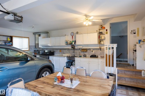 Garage space featuring a kitchen setup with white cabinetry and a stainless steel stove - 6407 163 Avenue Nw, Edmonton, AB 