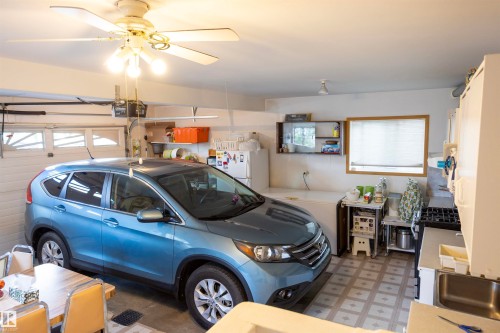 Spacious garage featuring a ceiling fan with integrated lighting, a utility sink, and ample counter space - 6407 163 Avenue Nw, Edmonton, AB 