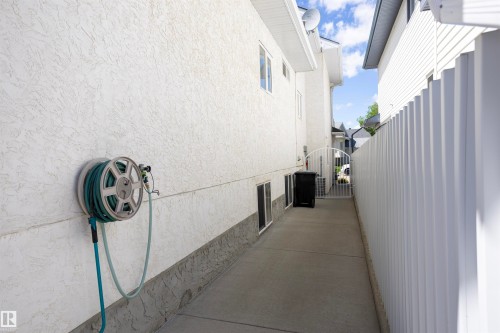 Stucco exterior with a concrete pathway and white privacy fencing - 6407 163 Avenue Nw, Edmonton, AB 