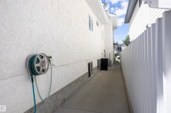 Stucco exterior with a concrete pathway and white privacy fencing - 