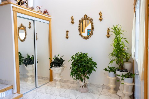 White wall with an ornate gold-framed mirror, flanked by decorative wall sconces - 6407 163 Avenue Nw, Edmonton, AB 