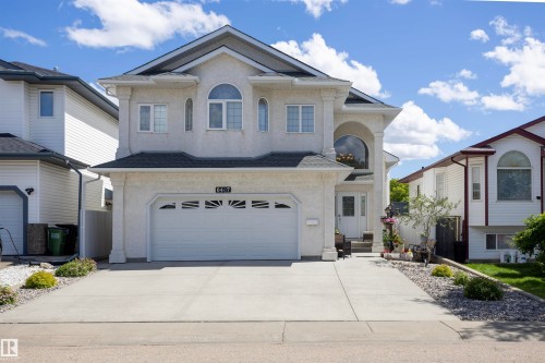 Stucco exterior with a peaked roofline, arched window, and prominent front entrance - 6407 163 Avenue Nw, Edmonton, AB 