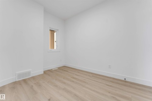 White wall interior featuring light wood-finish flooring, a single window, and a white baseboard trim - 4234 63 Street, Beaumont, AB - Indoor Photo Showing Other Room