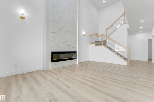 Living area featuring a floor-to-ceiling fireplace with stone-look tile surround and an integrated linear electric fireplace - 4234 63 Street, Beaumont, AB - Indoor With Fireplace