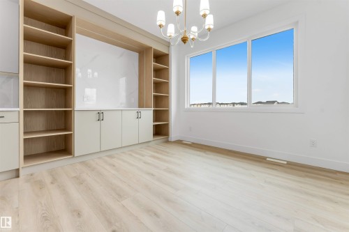 Built-in cabinetry with wood-finish shelving and central storage, complemented by a white marble-look panel - 4234 63 Street, Beaumont, AB - Indoor Photo Showing Other Room