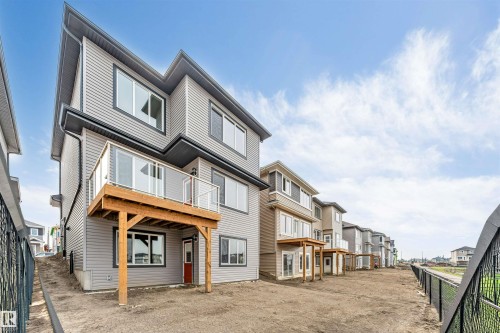 Contemporary multi-level residence featuring grey horizontal siding and a red entry door - 4234 63 Street, Beaumont, AB - Outdoor