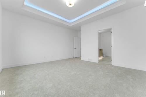 Spacious room featuring light gray carpeting, crisp white walls, and a recessed tray ceiling with accent lighting - 4234 63 Street, Beaumont, AB - Indoor Photo Showing Other Room