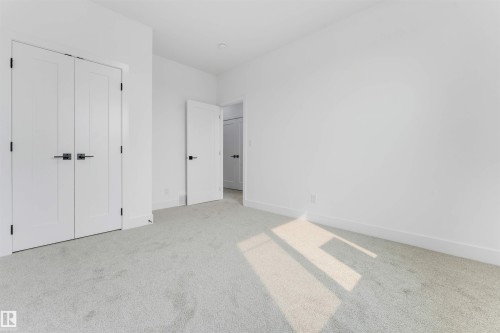 Bright room featuring light-colored carpeting, white walls, and modern white doors with matte black hardware - 4234 63 Street, Beaumont, AB - Indoor Photo Showing Other Room