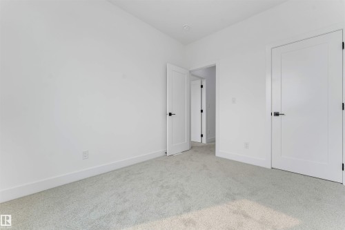 Interior room featuring light gray carpeting, white walls, and contemporary flat-panel doors with matte black hardware - 4234 63 Street, Beaumont, AB - Indoor Photo Showing Other Room