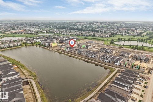 Aerial perspective showcasing a residential development bordering a natural pond - 4234 63 Street, Beaumont, AB - Outdoor With Body Of Water With View