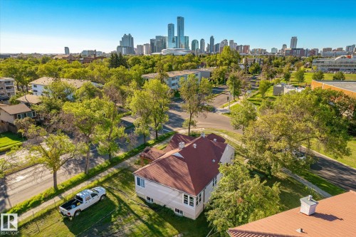 Residential property with a red-shingled roof, featuring a surrounding green lawn and mature trees - 11008 109 Street Nw, Edmonton, AB 