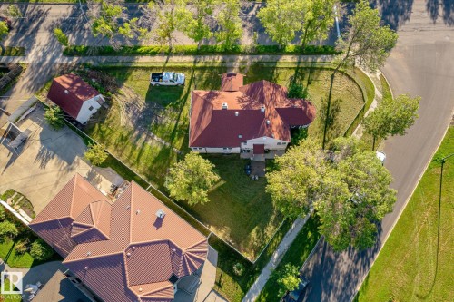 Property with a red-toned roof, expansive green lawn, and mature trees - 11008 109 Street Nw, Edmonton, AB 