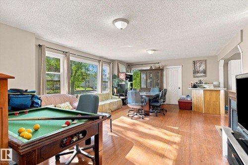 Expansive room featuring wood-finish flooring, multiple windows, and a built-in breakfast bar - 11008 109 Street Nw, Edmonton, AB 