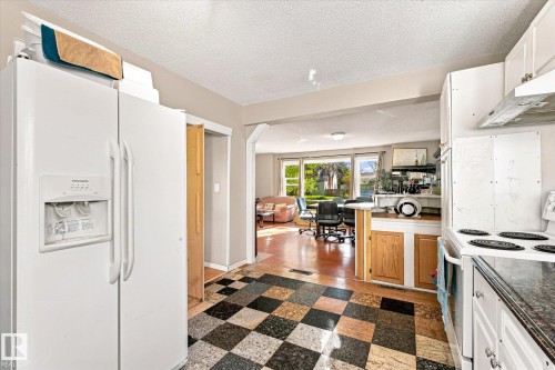 Kitchen featuring checkerboard flooring, white appliances, and wood-finish lower cabinetry - 11008 109 Street Nw, Edmonton, AB 