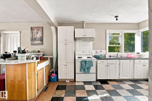 Kitchen featuring white cabinetry, a tiled backsplash, and a checkered floor pattern - 11008 109 Street Nw, Edmonton, AB 