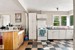 Kitchen featuring white cabinetry, a tiled backsplash, and a checkered floor pattern - 