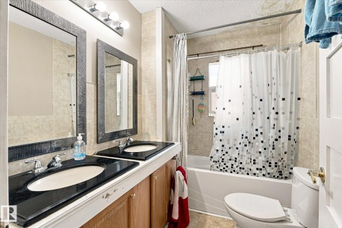 Dual vanity with dark countertops and integrated sinks, complemented by individual framed mirrors - 11008 109 Street Nw, Edmonton, AB 