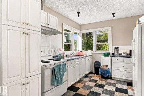 White cabinetry, checkerboard flooring, white tile backsplash, built-in range hood, and multiple windows - 11008 109 Street Nw, Edmonton, AB 