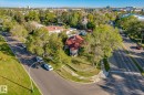 Corner lot property featuring a red tile roof, mature trees, and a concrete perimeter wall - 11008 109 Street Nw, Edmonton, AB 