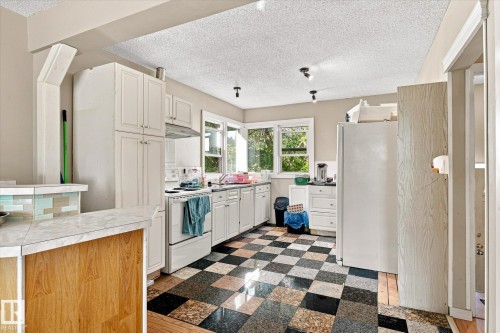 White cabinetry with ample storage, checkerboard flooring, integrated oven, and a tiled breakfast bar - 11008 109 Street Nw, Edmonton, AB 