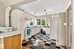 White cabinetry with ample storage, checkerboard flooring, integrated oven, and a tiled breakfast bar - 