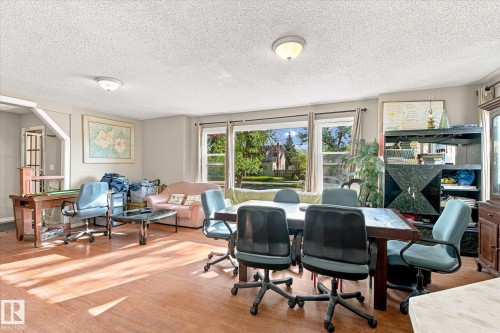 Wood-finish flooring throughout the open-concept room with multiple windows - 11008 109 Street Nw, Edmonton, AB 
