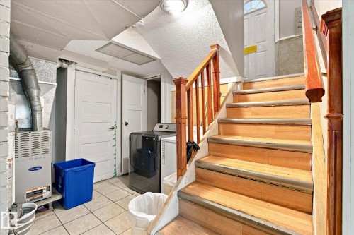 Hardwood stairs with wood railings, tile flooring, and white panel doors - 11008 109 Street Nw, Edmonton, AB 