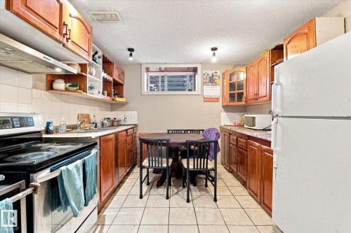 Kitchen featuring tile flooring, wood-finish cabinetry, a white tile backsplash, and a window - 11008 109 Street Nw, Edmonton, AB 