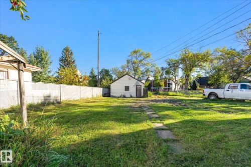Expansive grassy yard with a chain-link perimeter fence, concrete stepping stones, and a detached structure - 11008 109 Street Nw, Edmonton, AB 