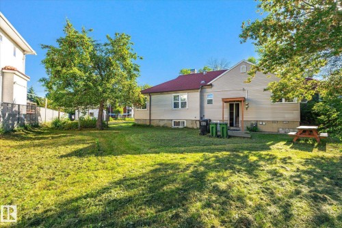 Expansive rear yard featuring a large grass area, mature trees, and privacy fencing - 11008 109 Street Nw, Edmonton, AB 