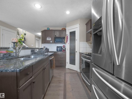 Kitchen featuring an undermount double-basin sink, granite countertops, stainless steel appliances, and wood-finish flooring - 1216 29 Avenue Nw, Edmonton, AB - Indoor Photo Showing Kitchen With Stainless Steel Kitchen With Double Sink With Upgraded Kitchen